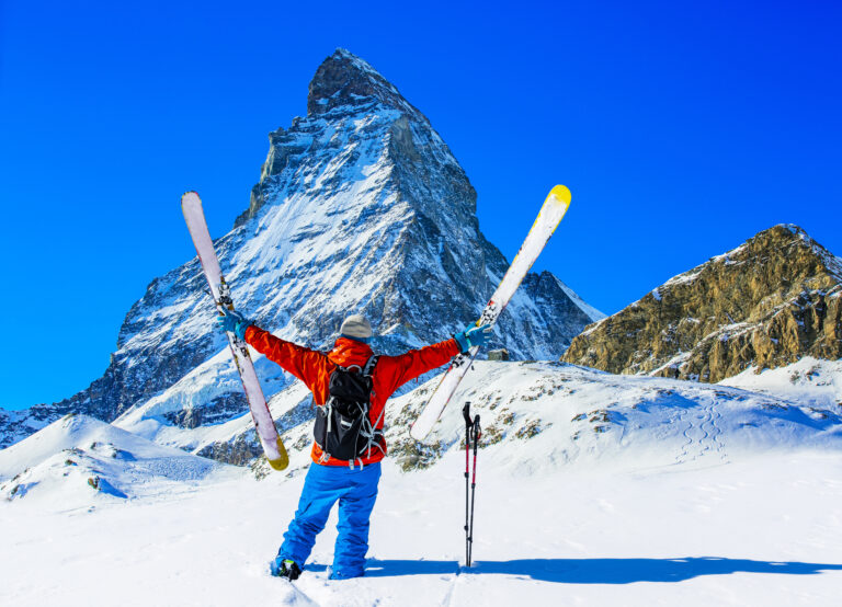 Alpin Luxe Ski Vacations - Skier Holds up Skis in Front of the Matterhorn